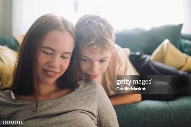 smiling teenage girl with brother lying on sofa at home - autistic girl stock pictures, royalty-free photos & images
