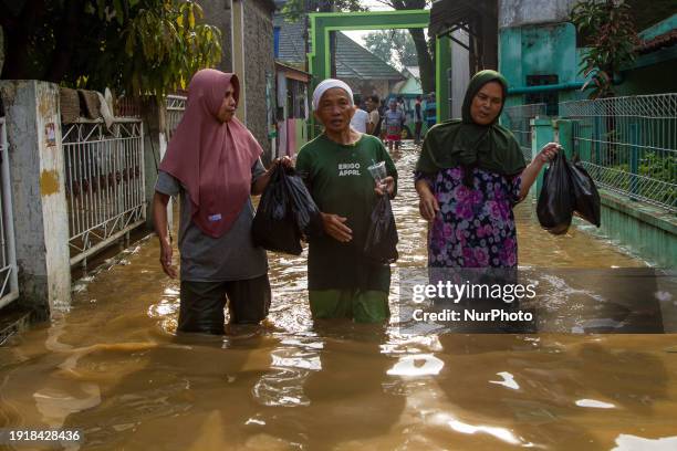 Women are passing through floods in Dayeuhkolot, Bandung Regency, Indonesia, on January 12, 2024. The overflow of the Citarum River, due to the high...