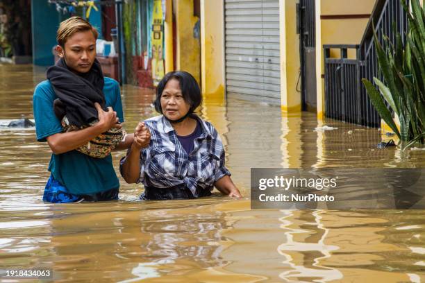 People are passing through floods in Dayeuhkolot, Bandung Regency, Indonesia, on January 12, 2024. The Citarum River is overflowing due to the high...