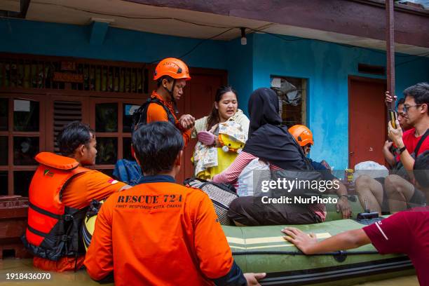 Rescue workers are evacuating a mother, baby, and toddler during flooding in Dayeuhkolot. The overflow of the Citarum River, due to the high...