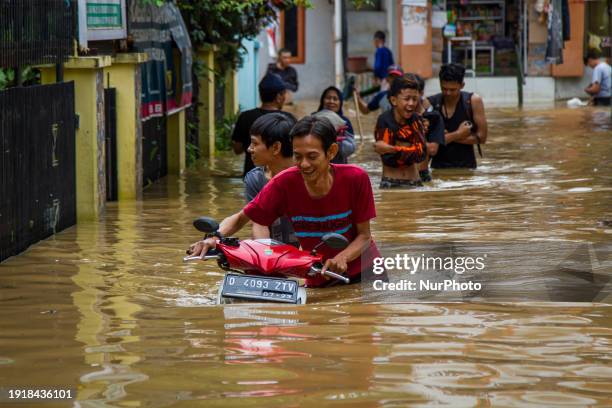 Man is passing through the flood with his motorcycle in Dayeuhkolot. The Citarum River overflowed due to the high intensity of rainfall in the...