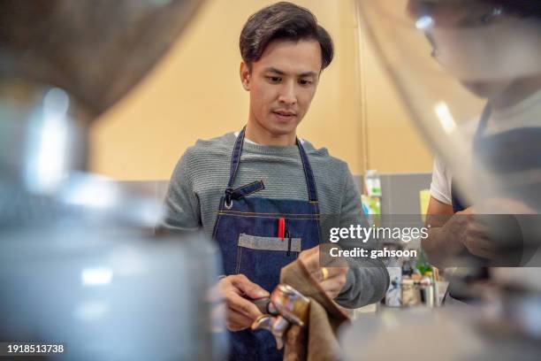 barista is cleaning the coffee equipment - malaysia man stock pictures, royalty-free photos & images