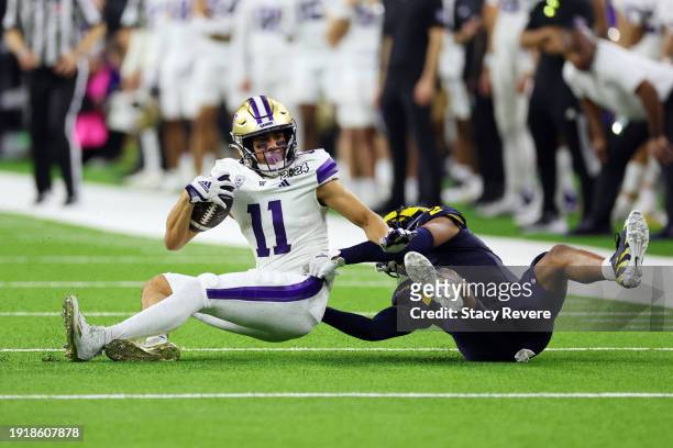 Jalen McMillan of the Washington Huskies is tackled by Will Johnson of the Michigan Wolverines in the fourth quarter during the 2024 CFP National...
