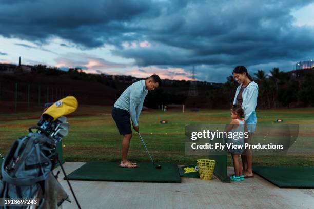 family having fun a the golfing range - eurasian people stock pictures, royalty-free photos & images