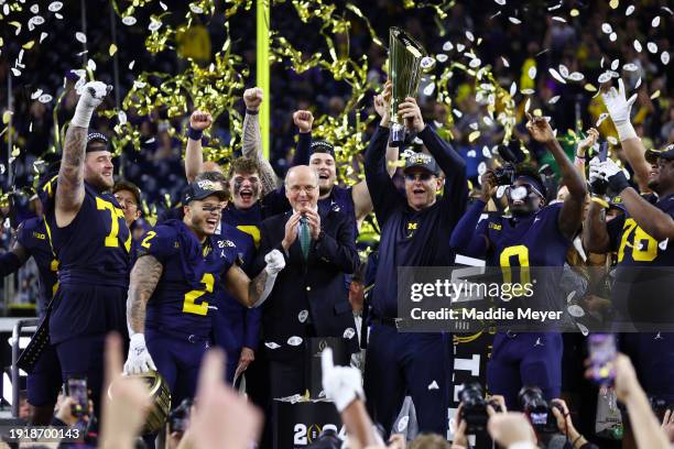 Head coach Jim Harbaugh of the Michigan Wolverines and his team react as he lifts the national championship trophy after defeating the Washington...