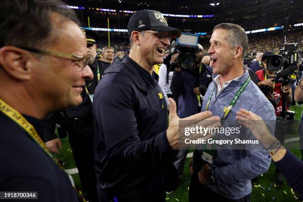 Head coach Jim Harbaugh of the Michigan Wolverines celebrates with his brother, and NFL head coach, John Harbaugh after defeating the Washington...