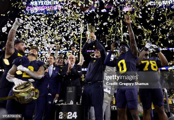 Head coach Jim Harbaugh of the Michigan Wolverines and his team react as he lifts the national championship trophy after defeating the Washington...