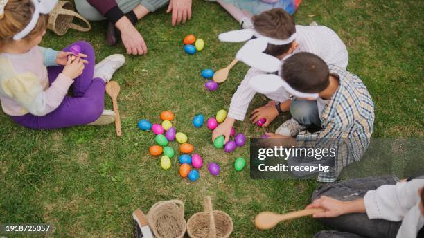 group of children and parents gathering at family garden for easter event - easter egg hunt stock-fotos und bilder