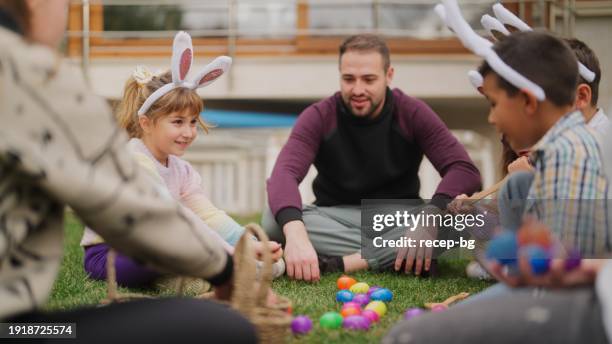 group of children and parents gathering at family garden for easter event - easter bunny man stockfoto's en -beelden