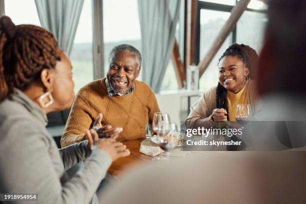 happy black family talking during a meal at dining table. - black family eating dinner together stock pictures, royalty-free photos & images