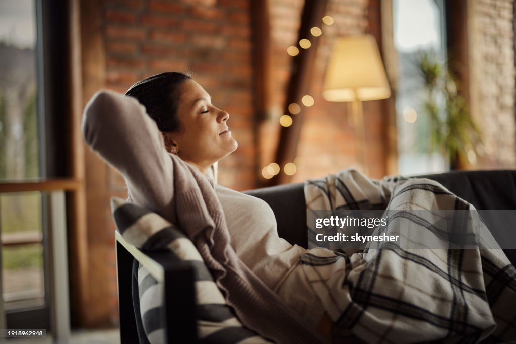 Smiling woman relaxing on sofa in the living room.