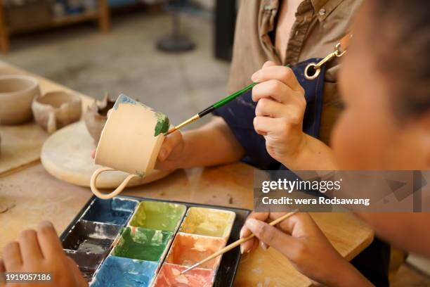 hand of woman coloring on clay pottery workshop - black sculptor stock pictures, royalty-free photos & images