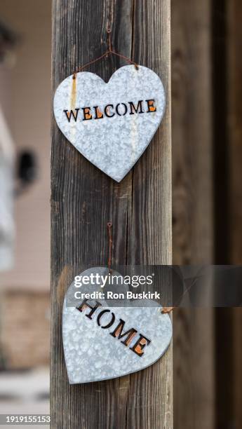 welcome home message in galvanized metal hearts on a wood post - welcome home stock pictures, royalty-free photos & images