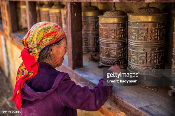 old tibetan woman turning the prayer wheels, upper mustang - tibet stock photos et images de collection