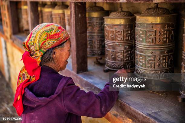 old tibetan woman turning the prayer wheels, upper mustang - prayer wheel stock pictures, royalty-free photos & images