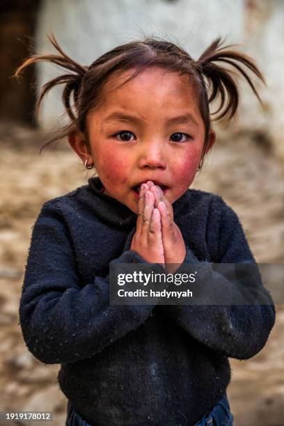 namaste! portrait of tibetan little girl, upper mustang, nepal - prayer pose greeting fotografías e imágenes de stock