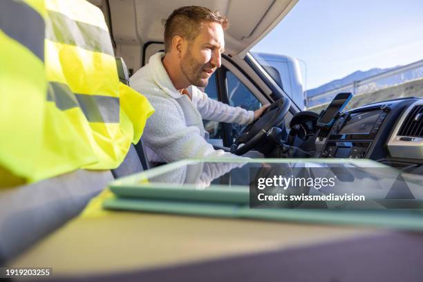 courier driver checking his schedule on a digital tablet inside of a delivery van - convoy stock pictures, royalty-free photos & images