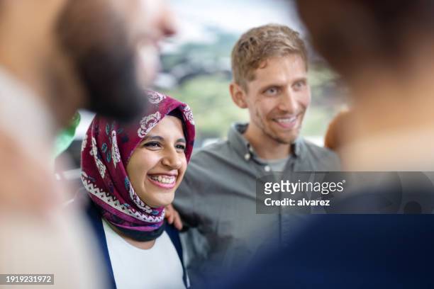 giovane donna d'affari musulmana in piedi in huddle con la squadra in ufficio - abbigliamento religioso foto e immagini stock