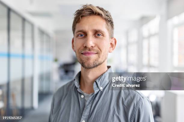 close-up portrait of confident businessman standing in office - homem imagens e fotografias de stock