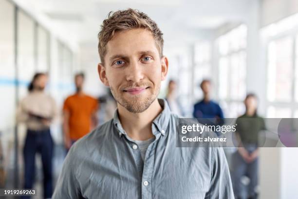 porträt eines startup-unternehmers mit team im hintergrund im büro - anführer stock-fotos und bilder