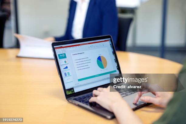 gros plan d’une femme préparant un rapport d’activité sur un ordinateur portable assis au bureau - moustiquaire photos et images de collection
