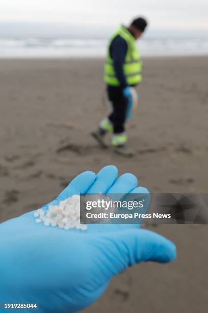 Worker catches plastic pellets with his hand, at Otur beach, on January 9 in Valdes, Asturias, Spain. The Principality of Asturias has activated an...