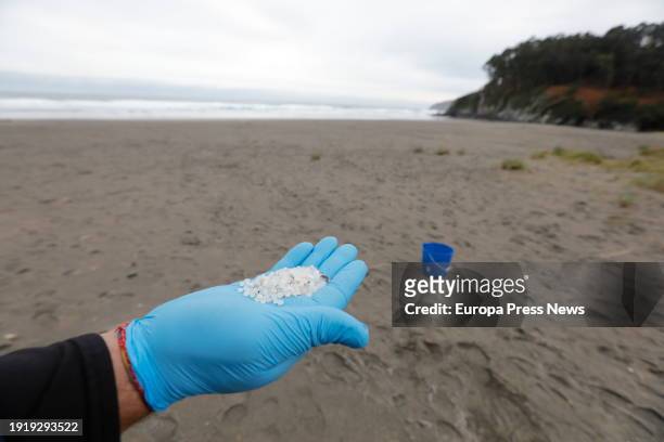 Worker catches plastic pellets with his hand, at Otur beach, on January 9 in Valdes, Asturias, Spain. The Principality of Asturias has activated an...
