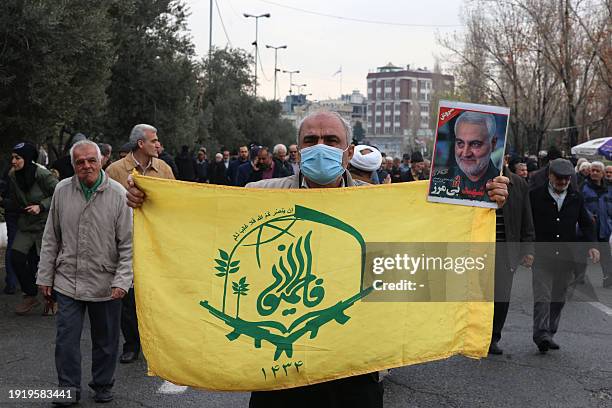 An protester holds the flag of the Afghan Shiite group Liwa Fatemiyoun, a militia formed in 2014 to fight in Syria on the side of the regim, during a...