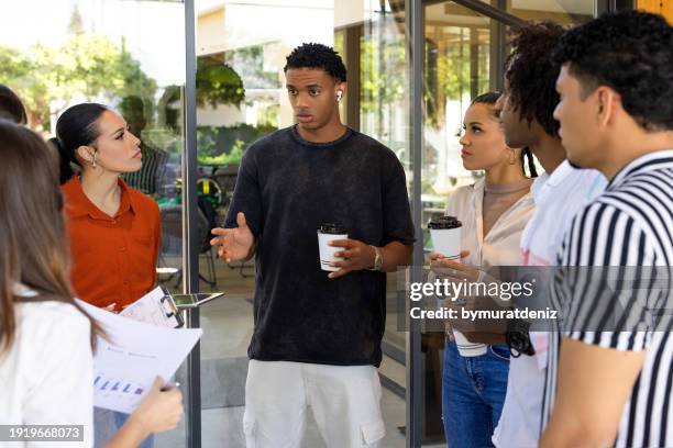 colleagues standing in a small group discussing something - about us stock pictures, royalty-free photos & images
