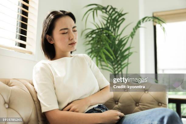 asian woman with stomach ache - mental illness stock pictures, royalty-free photos & images