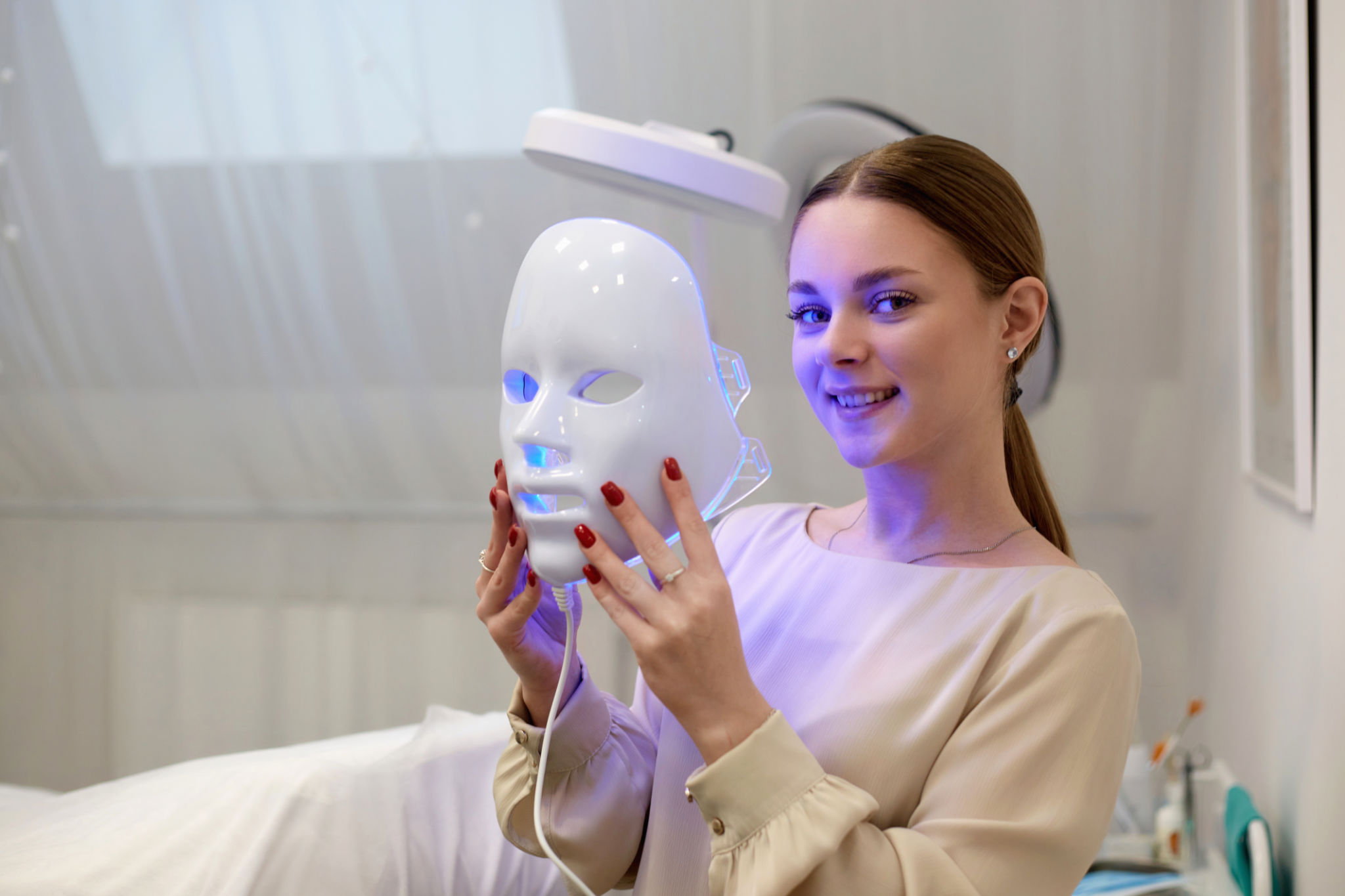 Beautiful young woman getting a led light therapy mask treatment for her face Beautiful young woman getting a led light therapy mask treatment for her face