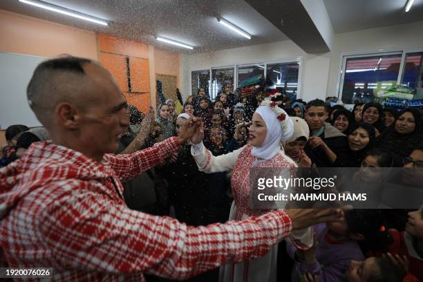Palestinian bride Afnan Jibril dances with her father during her wedding at the UNRWA School in the al-Salam neighborhood of Rafah, southern Gaza...