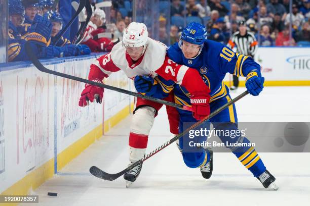 Henri Jokiharju of the Buffalo Sabres battles against Lucas Raymond of the Detroit Red Wings during an NHL game on December 5, 2023 at KeyBank Center...