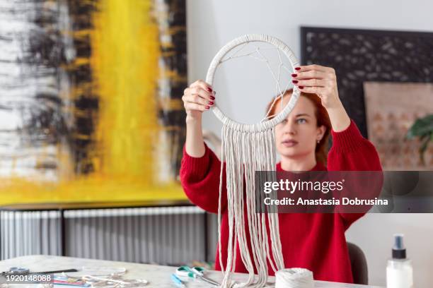 woman weaves macrame in living room - macrame stock pictures, royalty-free photos & images