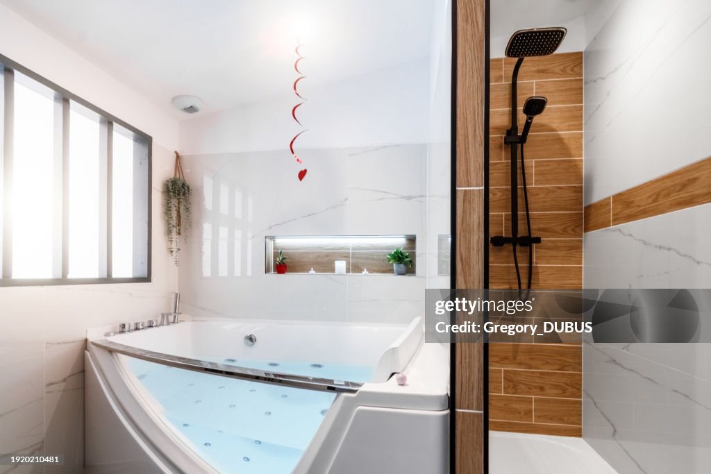 Luxurious bright bathroom in a cozy loft with a spa hot tub and a modern shower