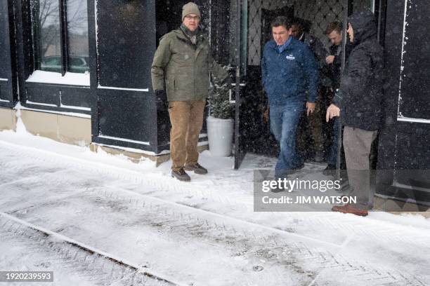 Florida Governor and 2024 Republican presidential hopeful Ron DeSantis is guided to his vehicle by staff as he departs a campaign stop in Ankeny,...