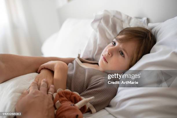 niño triste en la cama con dolor de estómago, gripe, resfriado, coronavirus, bronquitis o neumonía, virus o enfermedad infecciosa, midiendo la temperatura - diarrea fotografías e imágenes de stock