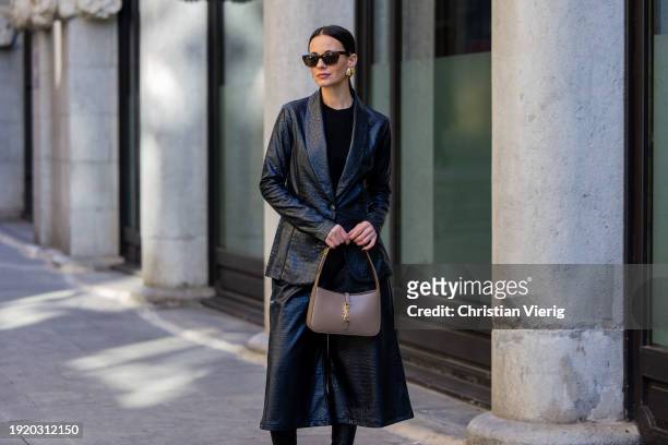Zina Charkoplia wears black culotte and blazer Assi, beige YSL bag, sunglasses, earrings on January 09, 2024 in Barcelona, Spain.