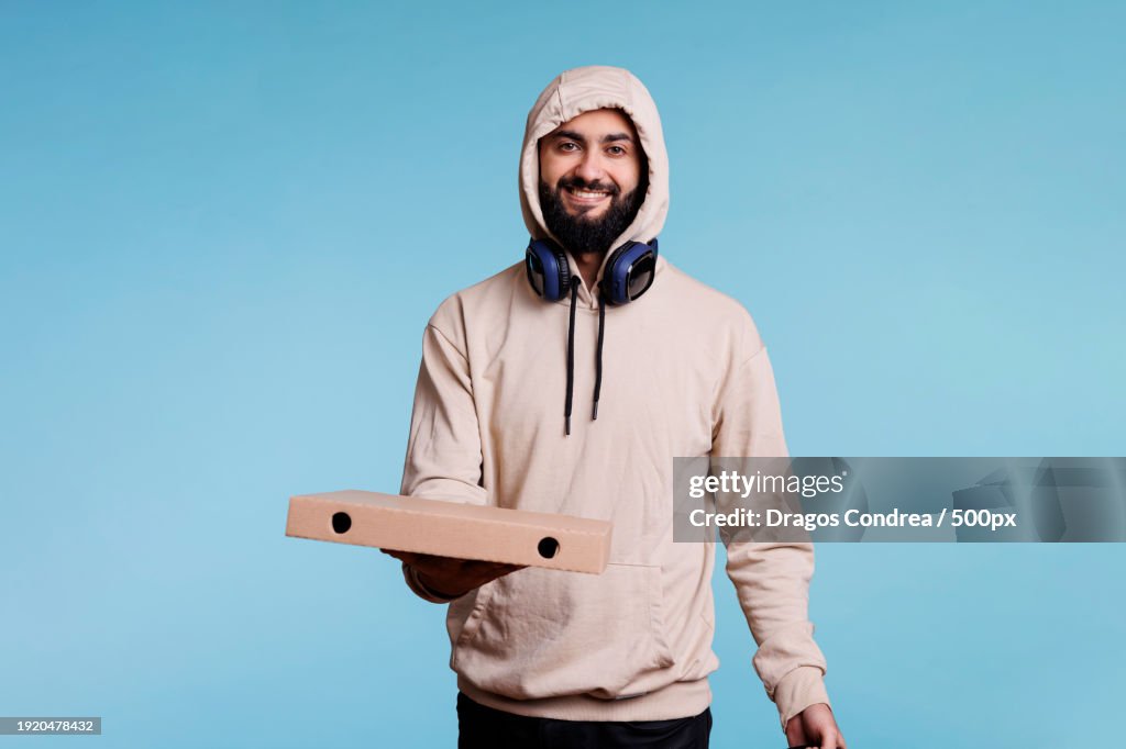 Smiling arab courier holding pizza box
