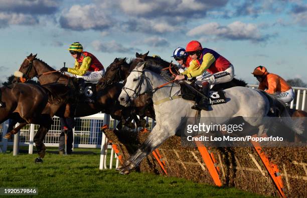 Horses and Jockeys traveling over the last fence during the Tokio Marine Kiln Steeple Chase, as the sun sets over the Betfair Tingle Creek Christmas...