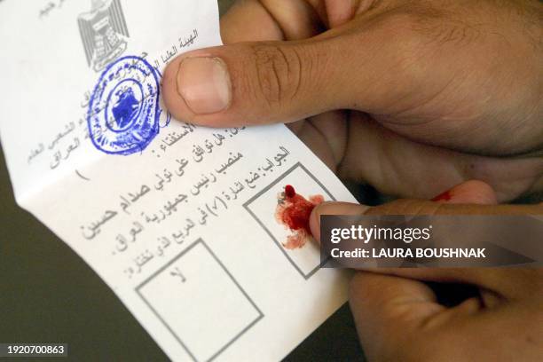 An Iraqi citizen casts his vote in blood 15 October 2002 at a polling centre in the city of Tikrit, Saddam Hussein's birthplace, some 170 kms north...