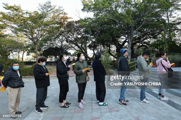 People wait in line to cast their ballots and vote in the presidential election at a polling station in a high school in Tainan on January 13, 2024.