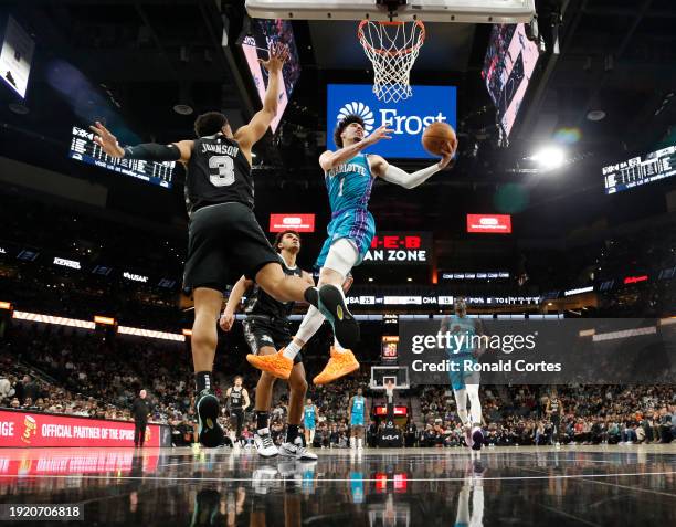 LaMelo Ball of the Charlotte Hornets scores past Keldon Johnson of the San Antonio Spurs in the first half at Frost Bank Center on January 12, 2024...