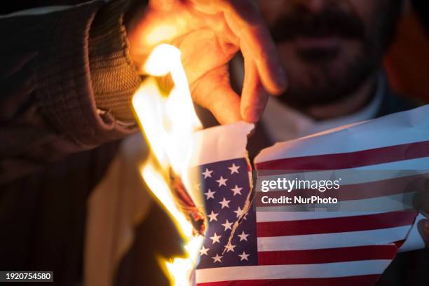 An Iranian protester is burning the U.S. Flag during an anti-U.S. And anti-British protest in front of the British embassy in downtown Tehran, Iran,...