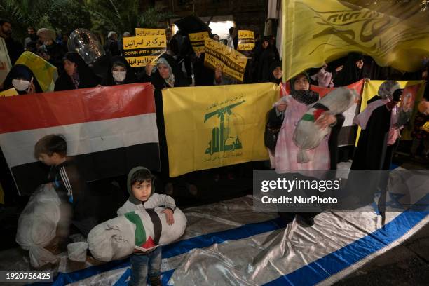 An Iranian female protester and two young boys are carrying packages wrapped in shrouds, symbolizing the bodies of Palestinian children, while...