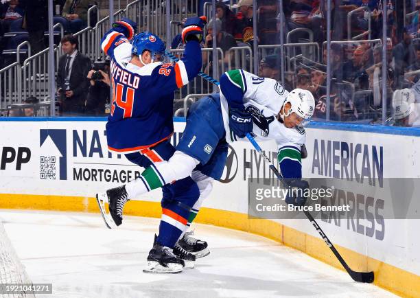 Scott Mayfield of the New York Islanders checks Dakota Joshua of the Vancouver Canucks during the third period at UBS Arena on January 09, 2024 in...