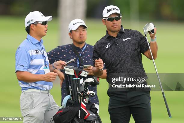 Hideki Matsuyama of Japan talks with his caddie Shota Hayafuji on the third hole during a practice round prior to the Sony Open in Hawaii at Waialae...