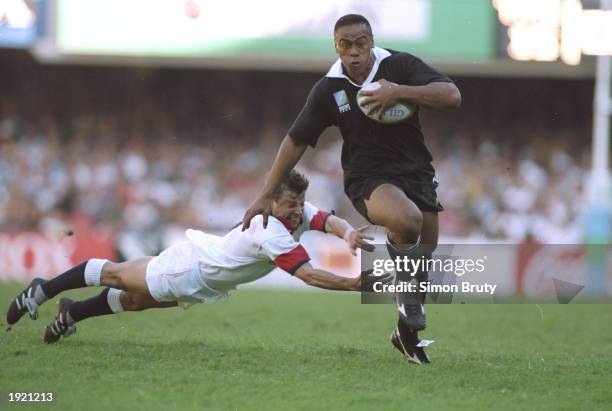 Jonah Lomu of New Zealand evades the diving tackle of Rob Andrew of England during the Rugby World Cup Semi Final at the Newlands Stadium in Cape...