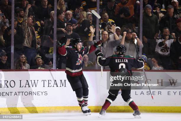 Nick Schmaltz of the Arizona Coyotes celebrates with Clayton Keller after scoring the game-winning goal in overtime against the Boston Bruins at...