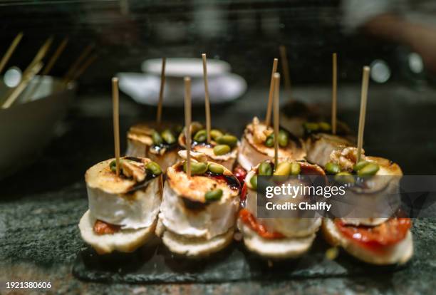 enjoying pintxos( pincho or tapas) in san sebastián,basque,spain - spaanse gerechten stockfoto's en -beelden